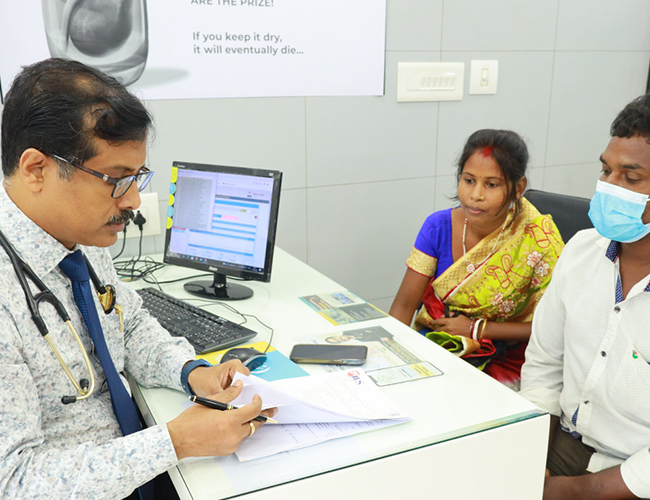 A doctor consults with their patient while seated at a desk.