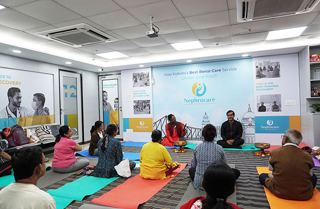 A group of people sitting on mats at a nephrocare event and doing meditation