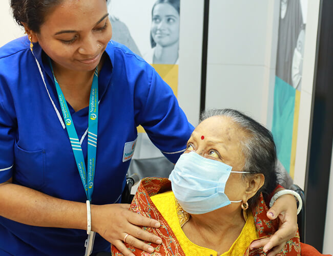 An old women wearing a mask and looking at nurse with a smiley face